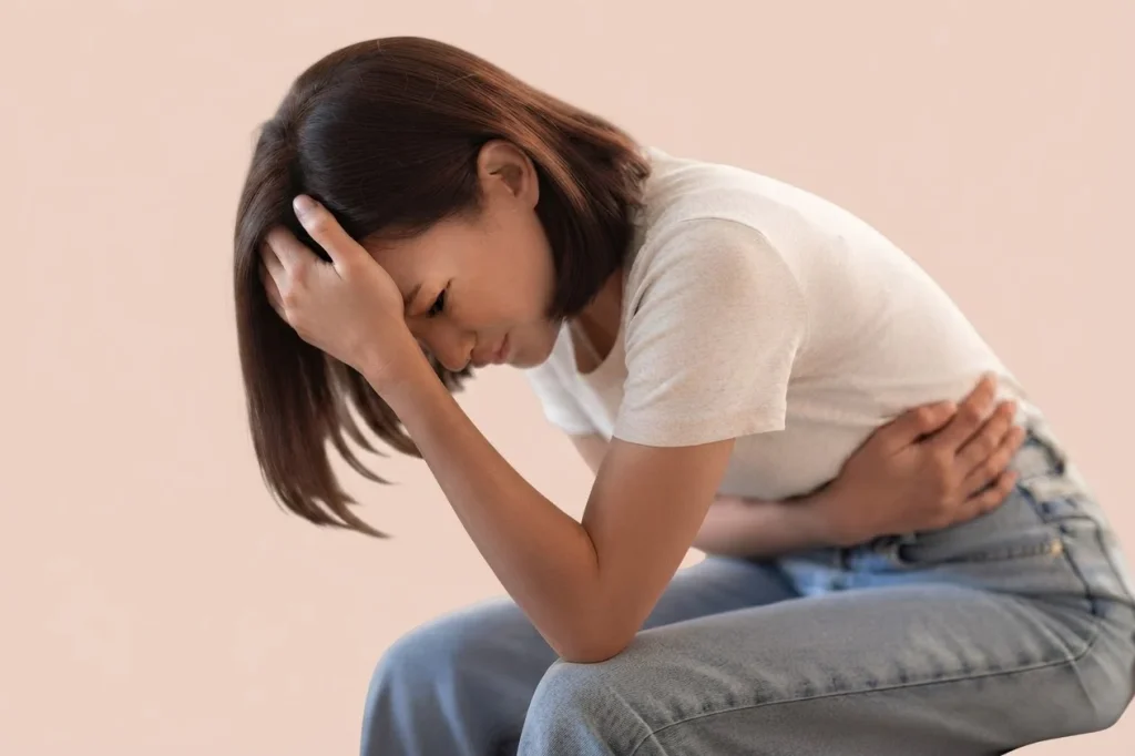 Femme assise, la tête dans la main, pliée par des tensions et le stress