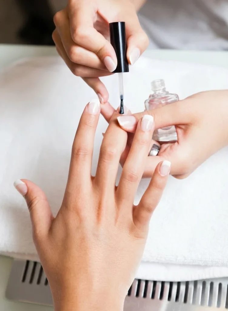 Pose d'un vernis transparent sur les ongles d'une main, pendant une manucure