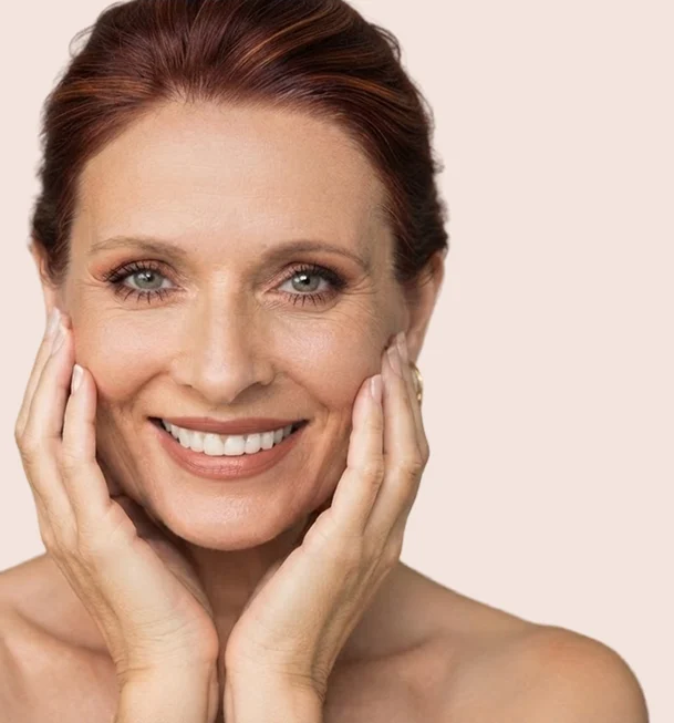 Femme d'âge mûr souriante, les mains posées sur les joues, teint reposé