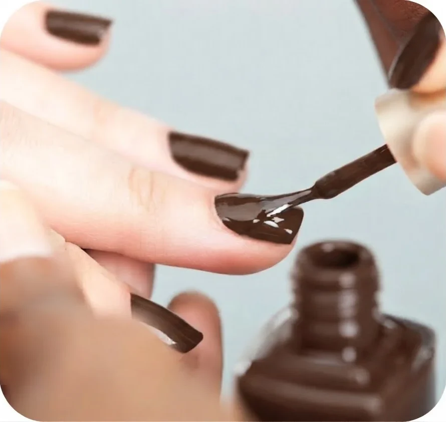 Application d'un vernis brun chocolat au pinceau sur un ongle