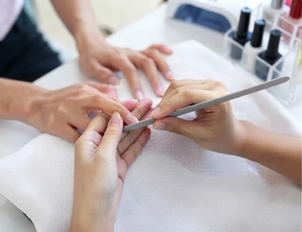 Limage des ongles d'une cliente pendant une manucure, produits en arrière-plan